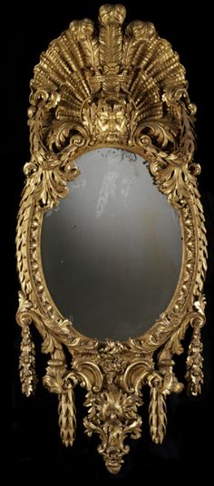 an ornately decorated gold mirror against a black background with the reflection of a bird on it