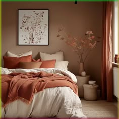 a bed with pillows and blankets on top of it next to a vase filled with flowers