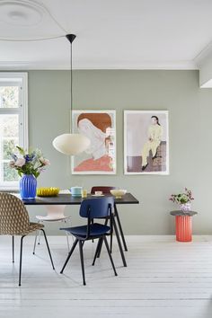 a dining room table with chairs and pictures on the wall