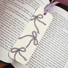 an open book with a purple ribbon on it