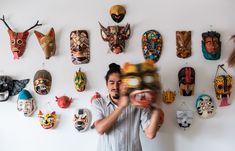 a man standing in front of a wall with masks on it