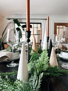 the table is set with candles, napkins and greenery for christmas dinner party