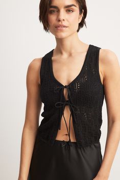 a woman wearing a black top with an open back and tie at the neckline