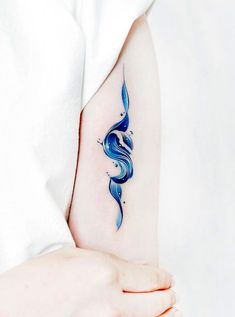 a woman's arm with a blue wave tattoo on the left side of her arm