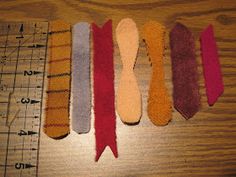 several different colored ties are lined up on a wooden table next to a ruler and measuring tape