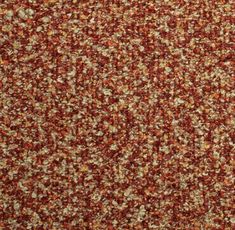 an orange and brown carpet with small white dots on the top right corner, is shown in close up