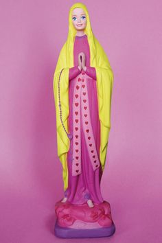 a figurine of the virgin mary on a pink background with hearts in her hands