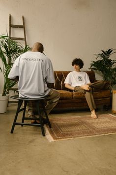 two people sitting on a couch in front of a rug