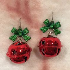 two red bells with green bows are on a white surface and one has a bell in the shape of a christmas tree ornament