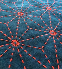 a blue table cloth with red stitching on it and an orange thread in the middle