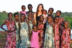 a woman posing for a photo with her children in front of a body of water