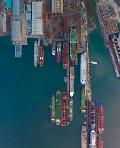 an aerial view of several boats docked at a dock in the water near some buildings