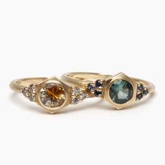 two gold rings with different colored stones on each one and the other handmade ring