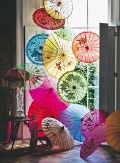 many colorful umbrellas are hanging in front of a window