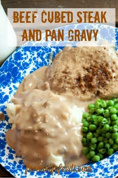 a blue and white plate topped with mashed potatoes, gravy and peas