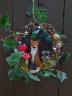 a fake fox is sitting in the middle of a wreath with mushrooms and leaves on it