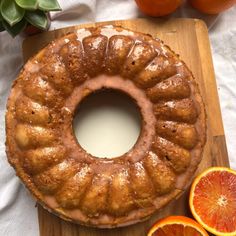 an orange bundt cake on a cutting board next to sliced oranges