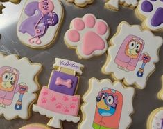 decorated cookies with cartoon characters on them are displayed in front of a metal tray,