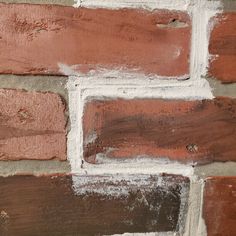 a brick wall that has been painted red and brown with white paint on the bricks