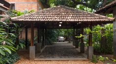 a car is parked in front of a wooden gazebo surrounded by greenery and trees