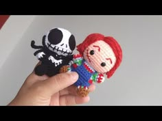 someone is holding two small crocheted dolls in their hands, one has a skull on it