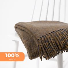 a brown and black blanket sitting on top of a white chair next to an orange tag