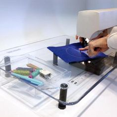 a woman is using a sewing machine to sew something on a piece of clear acrylic