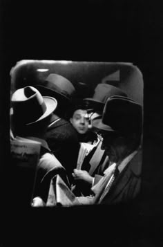 an old black and white photo of men with hats on their heads in a car