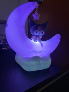 a cat sitting on top of a purple moon with stars hanging from it's sides