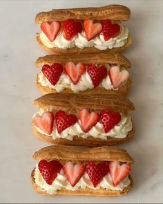 four sandwiches with strawberries and whipped cream on them are arranged in the shape of hearts