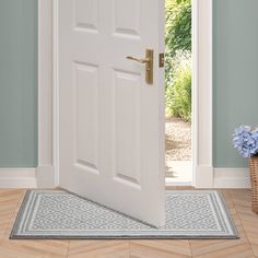 an open white door with a basket on the floor next to it and blue walls