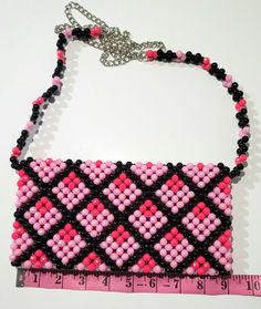 a pink and black beaded purse with a measuring tape