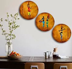 three round paintings on the wall above a dining room table with chairs and vases