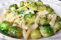 a white bowl filled with pasta and brussel sprouts on top of a table