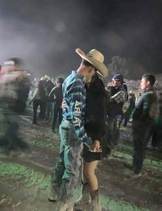 two people standing next to each other in front of a group of people wearing cowboy hats