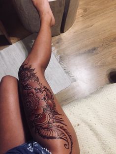 a woman's leg with a tattoo on it sitting next to a wooden table