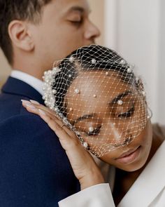 the bride and groom are embracing each other while wearing their veils over their heads