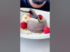 a man is cutting into a dessert with raspberries