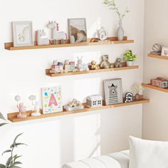 three wooden shelves with pictures and other items on them in a white living room setting