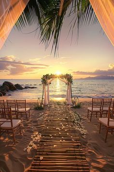 an outdoor wedding set up on the beach with white flowers and greenery at sunset