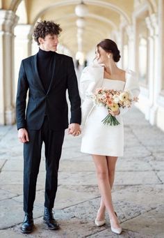 a man in a tuxedo and a woman in a white dress holding hands