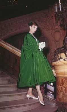 a woman in a green dress is walking down the stairs