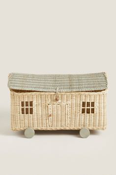 a wicker box with wheels holding a small doll house on it's side