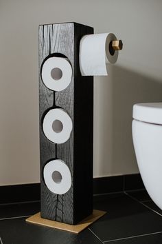 two rolls of toilet paper sitting on top of a wooden stand next to a toilet