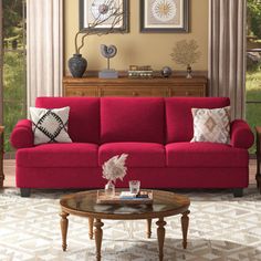 a living room with red couches and pictures on the wall above them, along with a coffee table