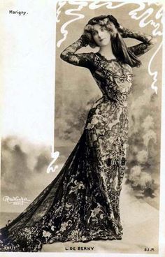 an old black and white photo of a woman in a long dress with her hands on her head