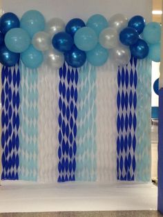 blue and white balloons are hanging on the wall in front of an arch decorated with streamers