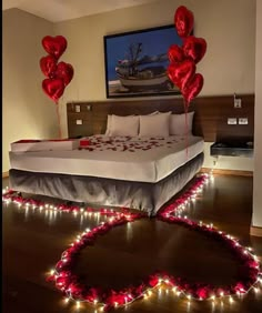 a bedroom decorated for valentine's day with heart shaped balloons and string lights on the floor