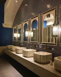 a row of sinks in a bathroom with mirrors on the wall and lights above them