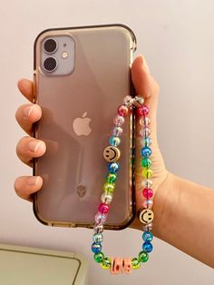 a person holding an iphone case with beaded bracelets attached to the back of it